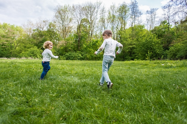 I bambini giocano sull&#39;erba verde all&#39;aperto, corrono e si divertono