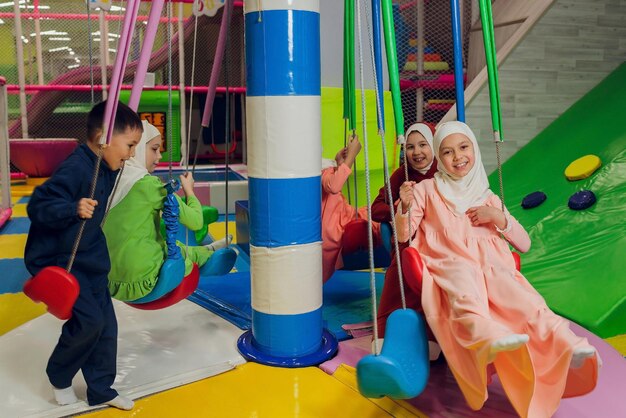 I bambini in abiti musulmani cavalcano un'altalena
