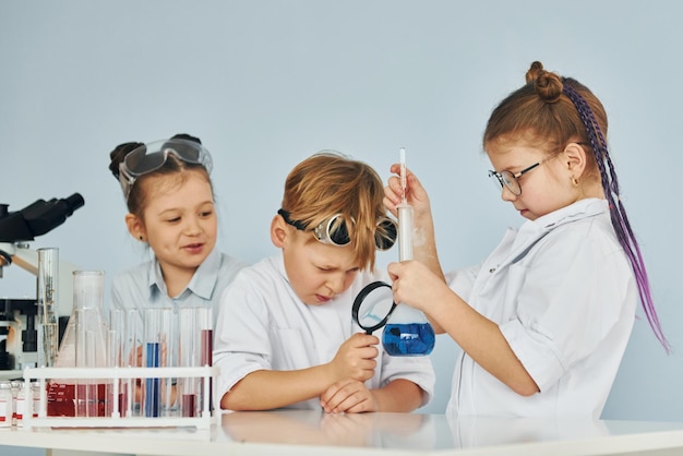 I bambini in camice bianco interpretano uno scienziato in laboratorio usando l'attrezzatura