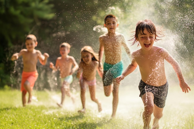 I bambini in costume da bagno corrono felicemente attraverso gli sprinkler in un ambiente naturale