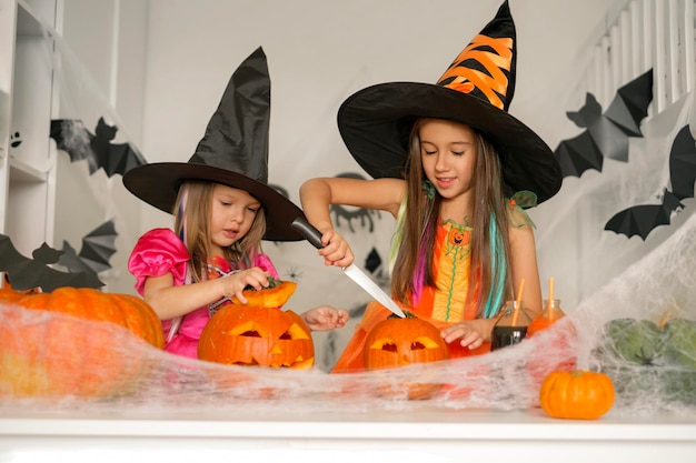 I bambini in costume da strega stanno intagliando zucche per Halloween