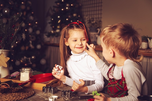 I bambini in cucina giocano con la farina. Decorazioni natalizie, tradizioni familiari, cibo natalizio, vigilia delle vacanze.