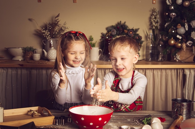 I bambini in cucina giocano con la farina. Decorazioni natalizie, tradizioni familiari, cibo natalizio, vigilia delle vacanze.