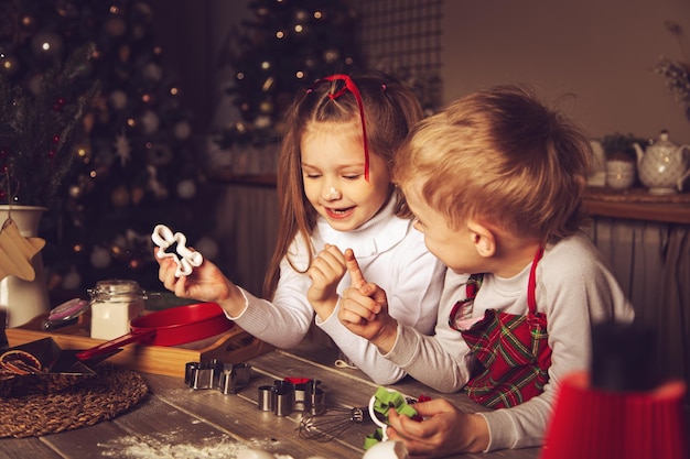 I bambini in cucina stanno preparando i biscotti. Decorazioni natalizie, tradizioni familiari, cibo natalizio, vigilia delle vacanze.