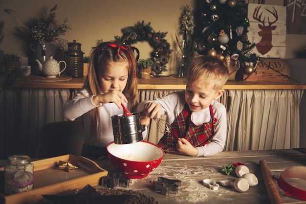 I bambini in cucina stanno preparando i biscotti. Decorazioni natalizie, tradizioni familiari, cibo natalizio, vigilia delle vacanze.