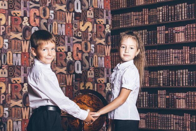 I bambini in età scolare considerano un mappamondo in biblioteca