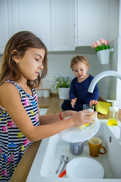 I bambini lavano i piatti in cucina. Messa a fuoco selettiva. Ragazzo.