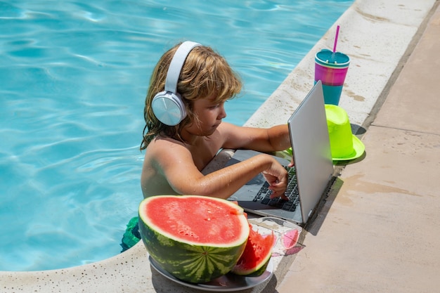 I bambini lavorano fuori con il laptop in piscina I bambini lavorano sul laptop dalla piscina Affari estivi