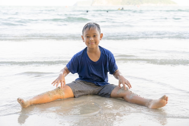 I bambini maschi stanno giocando felicemente al mare alla spiaggia.