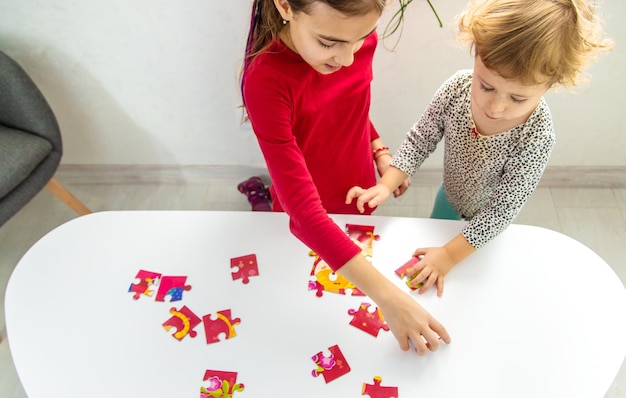 I bambini mettono insieme un puzzle sul tavolo Fuoco selettivo