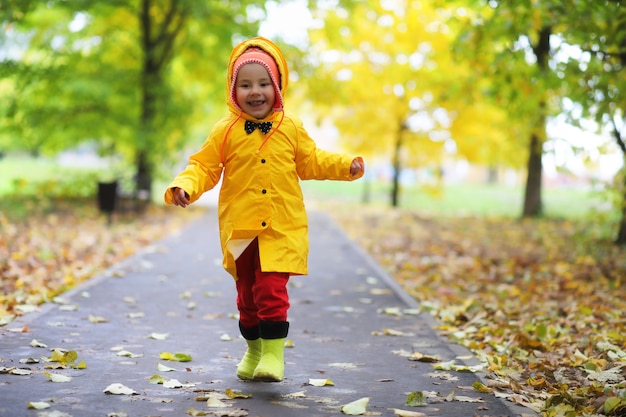 I bambini nel parco autunnale camminano con gli impermeabili durante il giorno