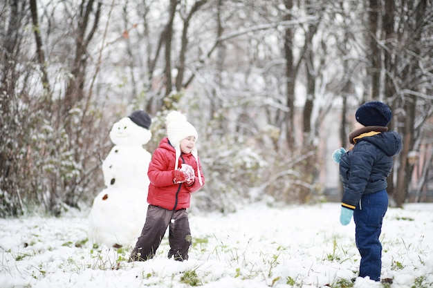 I bambini nel parco invernale giocano con la neve