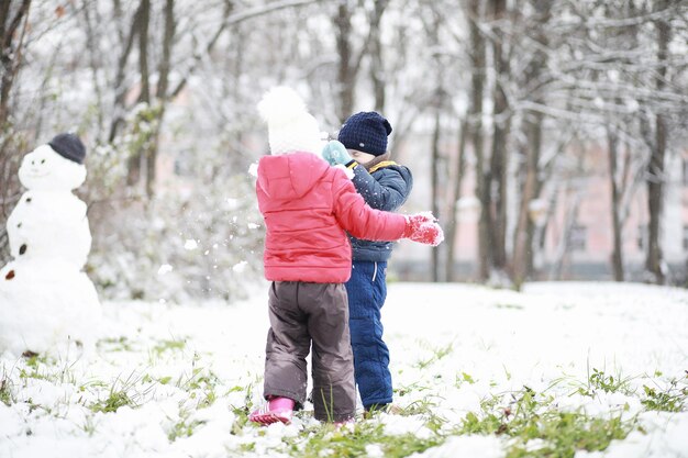 I bambini nel parco invernale giocano con la neve