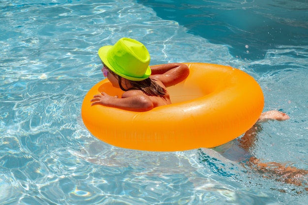 I bambini nuotano in piscina Vacanze per bambini e concetto di vacanza Ragazzino felice con l'arancia