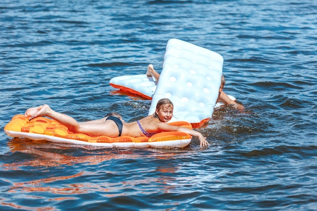 I bambini nuotano su materassini gonfiabili sull'acqua