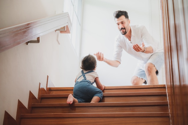 I bambini piccoli con il primo gradino a piedi con le scale a casa, i bambini piccoli sono felici di giocare e imparano a gattonare con la famiglia, un neonato carino che si diverte e si prende cura dell'infanzia