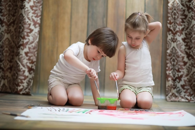 I bambini piccoli dipingono su un grande foglio di carta