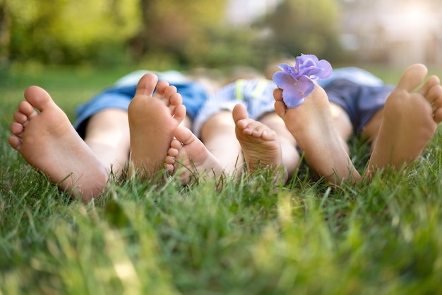 I bambini piccoli giacciono sull'erba nel parco in estate, le gambe dei bambini ravvicinate