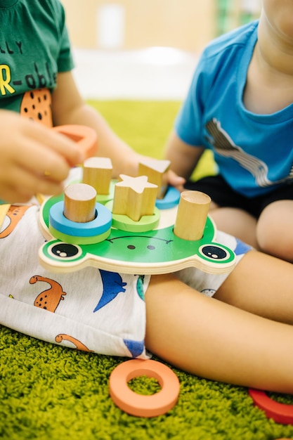 I bambini piccoli giocano con i giocattoli di legno nell'asilo