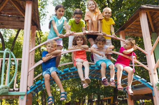 I bambini piccoli nel parco giochi stanno mostrando i pollici in su