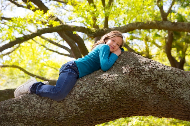 I bambini scherzano la ragazza che riposa la menzogne su un ramo di albero