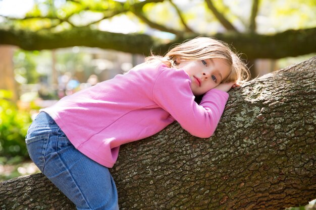 I bambini scherzano la ragazza che riposa la menzogne su un ramo di albero