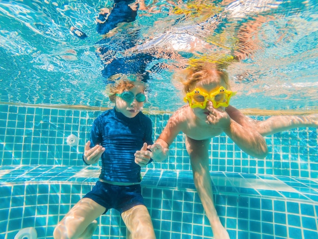 I bambini si divertono a giocare sott'acqua in piscina durante le vacanze estive