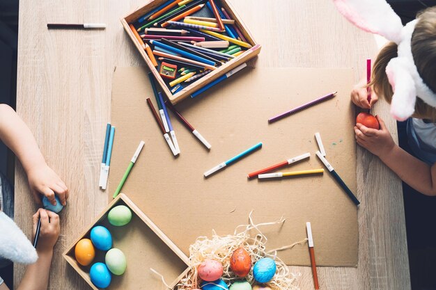 I bambini si preparano per la Pasqua I bambini dipingono le uova di Pasqua Vista dall'alto piatto dello sfondo di Pasqua