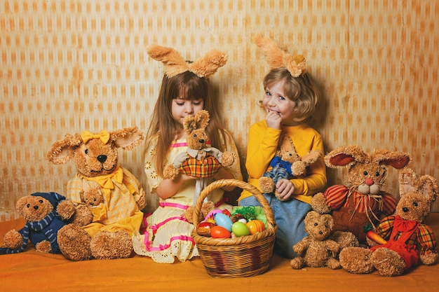 I bambini sono seduti su una coperta in mezzo allo stile vintage delle lepri pasquali.