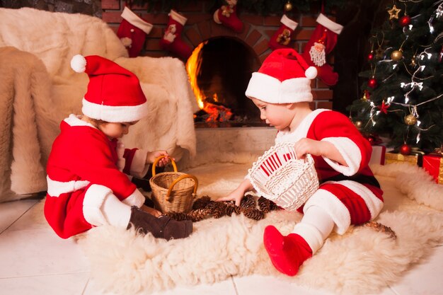 I bambini sono seduti vicino al caminetto e giocano con i coni - Decorazioni natalizie