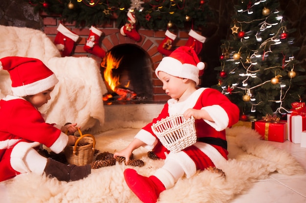 I bambini sono seduti vicino al caminetto e giocano con i coni - Decorazioni natalizie