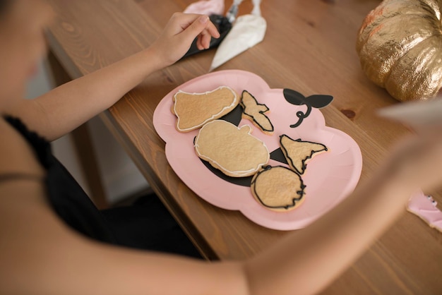 I bambini stanno colorando i biscotti di pan di zenzero per Halloween.