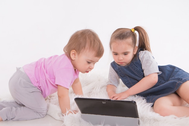 I bambini stanno guardando i cartoni animati sul tablet. Scuola a casa per le ragazze durante la quarantena