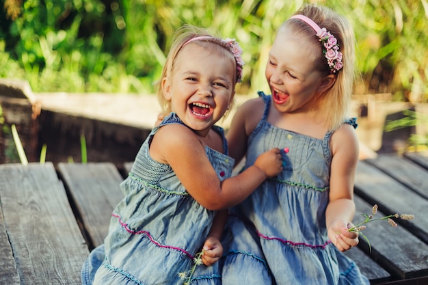 I bambini svegli felici di sorriso che si divertono giocano all'aperto abbracciano insieme. Infanzia, natura, vacanze, concetto di lifestyle per bambini