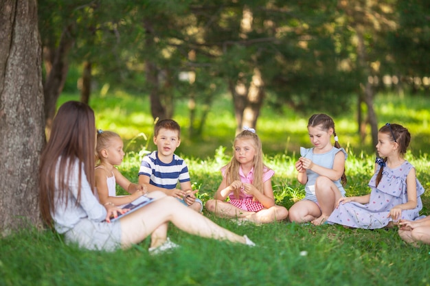 I bambini tengono una lezione con l'insegnante nel parco su un prato verde.