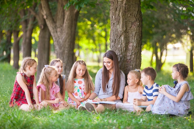 I bambini tengono una lezione con l'insegnante nel parco su un prato verde.