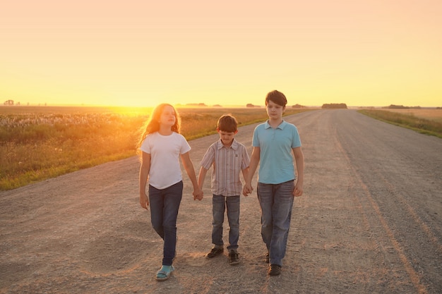 I bambini vanno sulla strada per incontrare il tramonto.