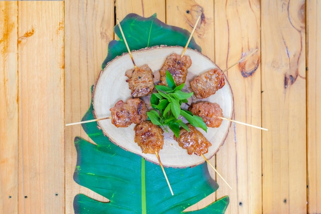 I bastoncini di maiale arrosto alla griglia cucinati sono disposti sulla foglia di banana nel giardino esterno