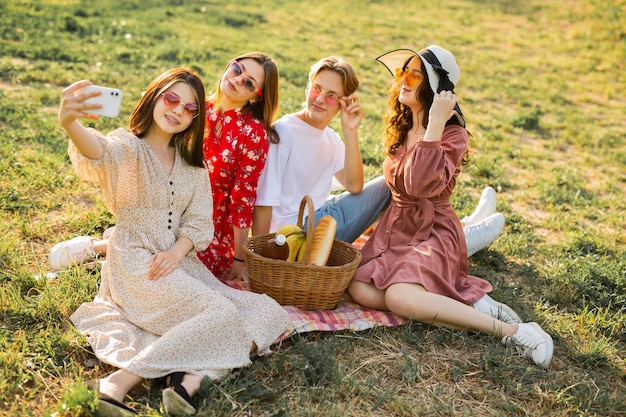 i bei giovani durante un picnic estivo vengono fotografati al telefono