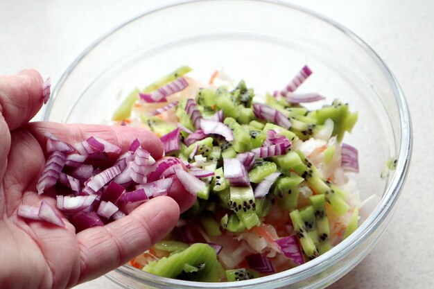 I benefici delle cipolle nelle insalate cipolle rosse vitaminiche sulla mano di una persona sullo sfondo di piatti di insalata