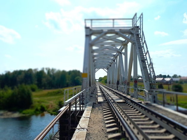 I binari della ferrovia su un fiume in una giornata di sole in estate Ponte ferroviario sul fiume