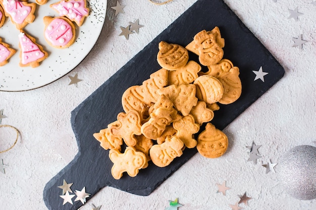 I biscotti di Natale appena sfornati sono impilati su una lavagna su un tavolo decorato. Trattamento festivo. Vista dall'alto. Avvicinamento