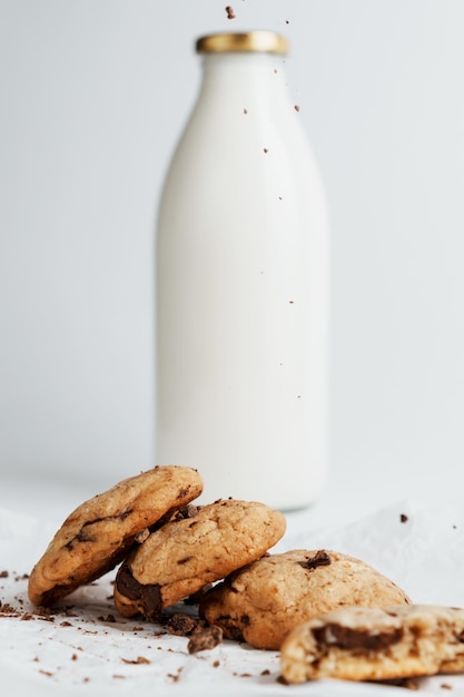 I biscotti fatti in casa sono cosparsi di cioccolato sullo sfondo di una bottiglia di latte