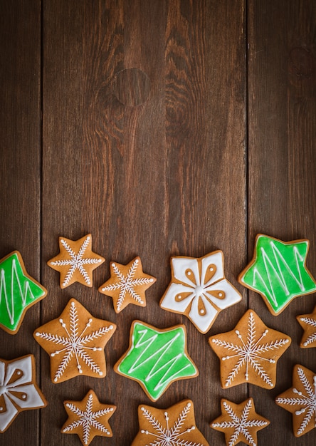 I biscotti festivi del pan di zenzero di Natale a forma di stella si trovano su un fondo di legno di marrone scuro.