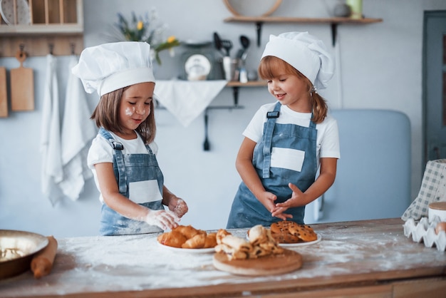 I biscotti sono pronti. Bambini di famiglia in uniforme bianca da chef che preparano il cibo in cucina.
