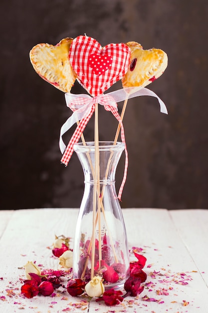 I biscotti spuntano a forma di cuore e cuore dal tessuto in un motivo una gabbia rossa con boccioli di rose