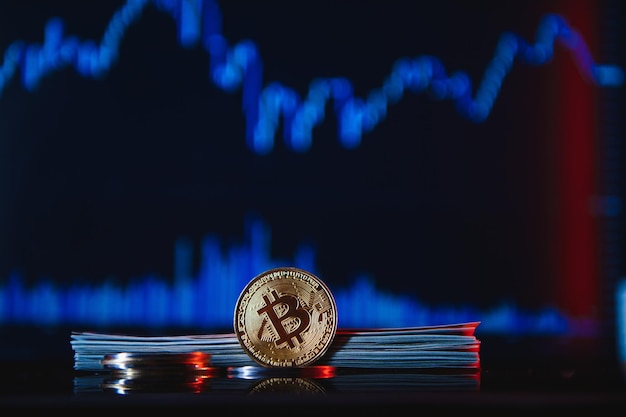 I bitcoin dorati sono impilati su uno sfondo luminoso di grafici aziendali in primo piano Criptovaluta Bitcoin Piegato in un tubo Banconote da 100 dollari