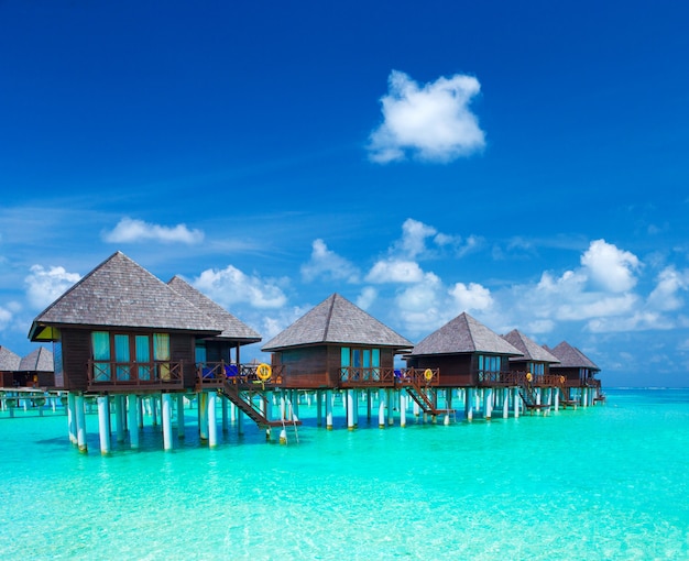 I bungalow dell'acqua delle Maldive ricorrono alla spiaggia delle isole. Oceano Indiano, Maldive. Splendido paesaggio marino, resort di lusso e cielo. Spiaggia sotto un cielo meraviglioso