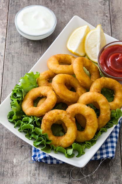 I calamari fritti suonano con lattuga e ketchup su superficie di legno