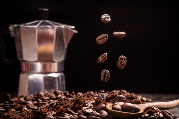 I chicchi di caffè che fluttuano in una scena nera selezionano il punto focale con un mogapot